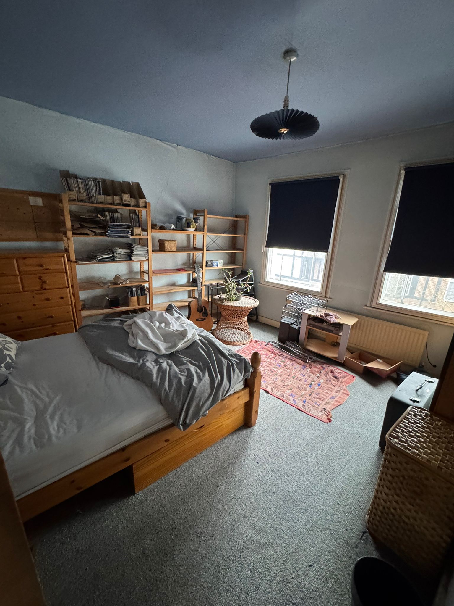 Bedroom with bedding and cluttered bookshelves